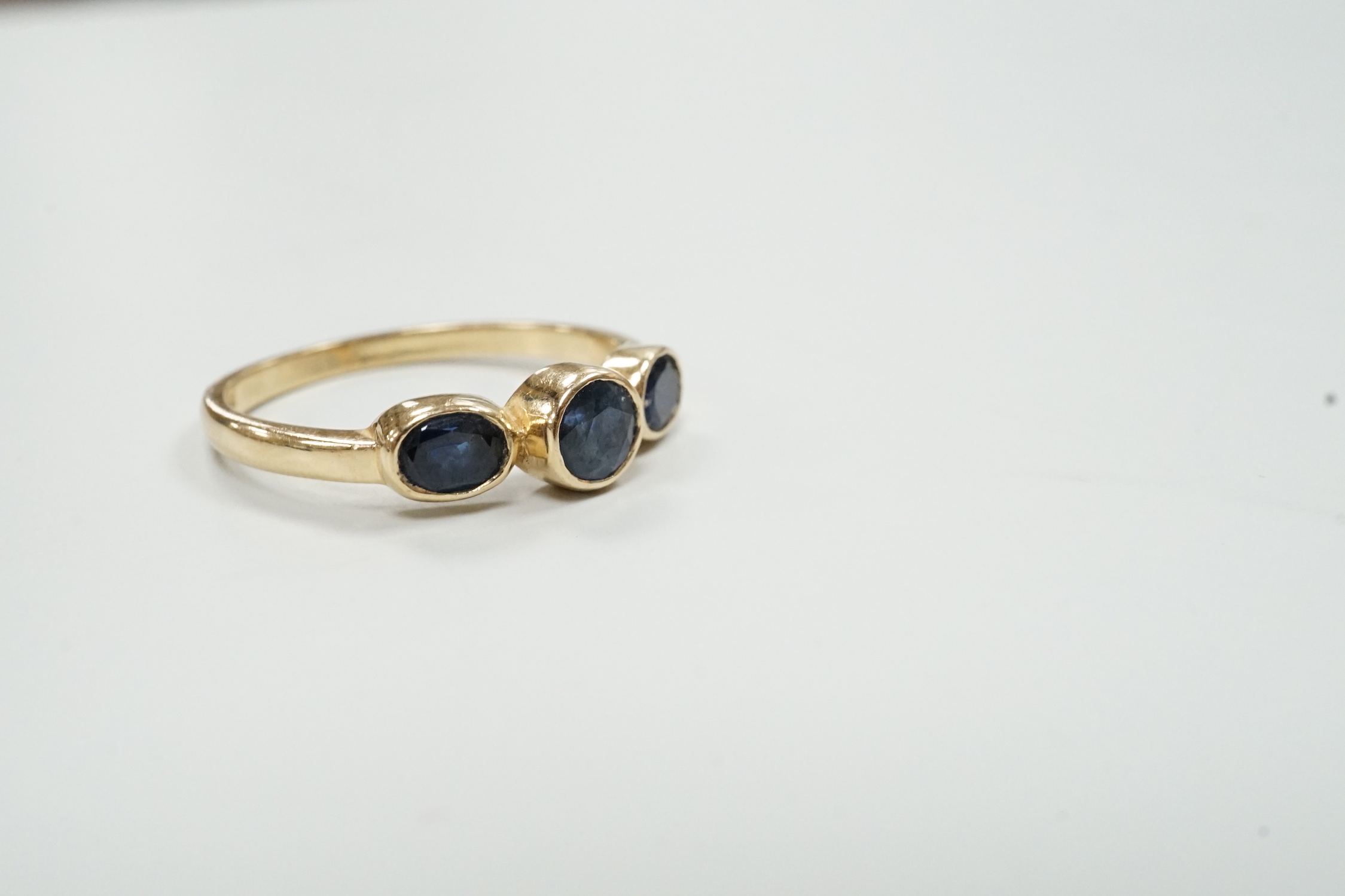 A modern 585 yellow metal and three stone sapphire set ring, size O, gross weight 2.4 grams.